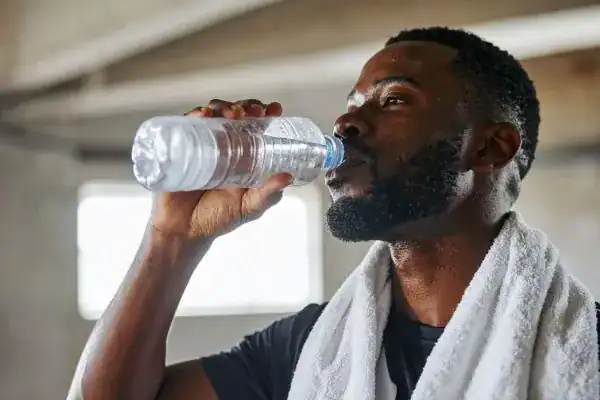Image of man drinking water to improve hydration Virginia Water after work out.